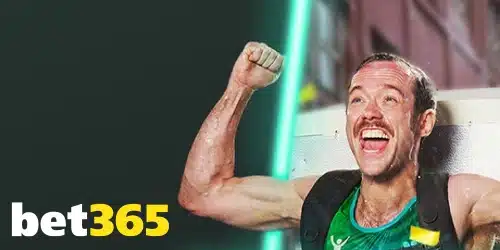 Bet365 logo in the bottom left corner. The main image shows a triumphant man with a mustache, raising his fist in the air with excitement. He is sweating, suggesting physical exertion, and wearing a green athletic tank top and a black backpack. The background has green and black diagonal lines and a bright green light.